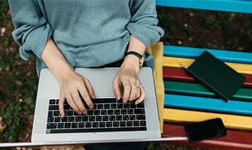 Sitting on colorful bench with laptop 